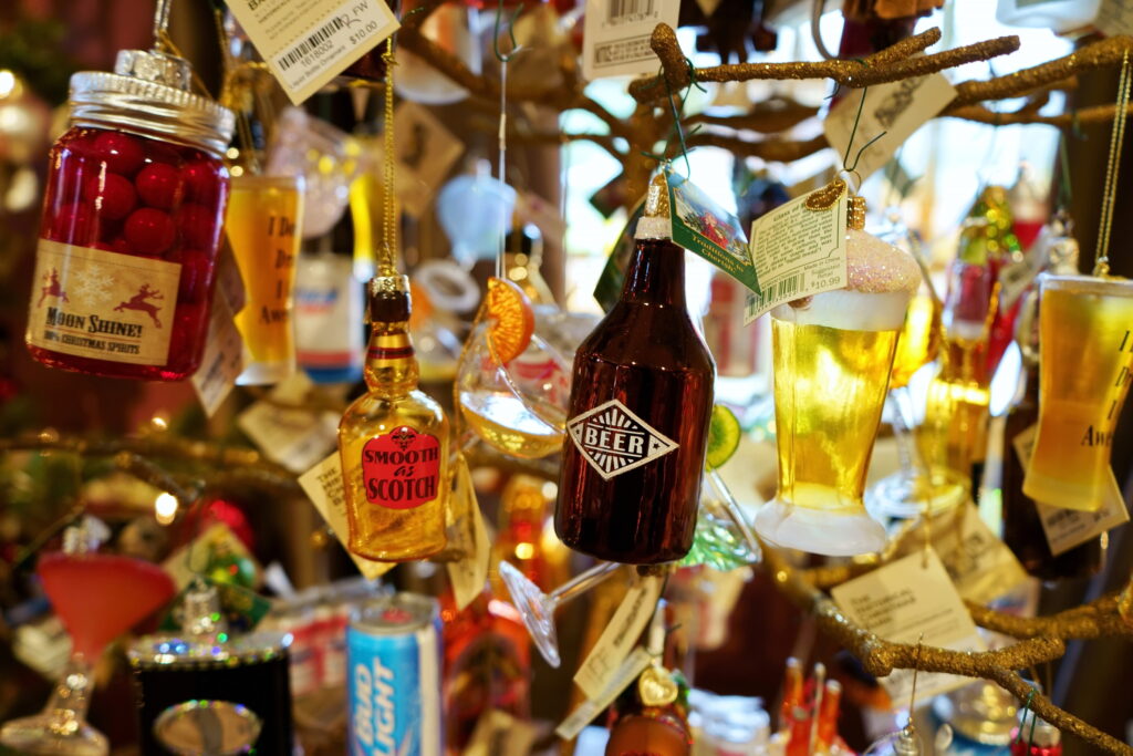 Photo of different bottles and glasses and cans of beer and spirits hanging from branches