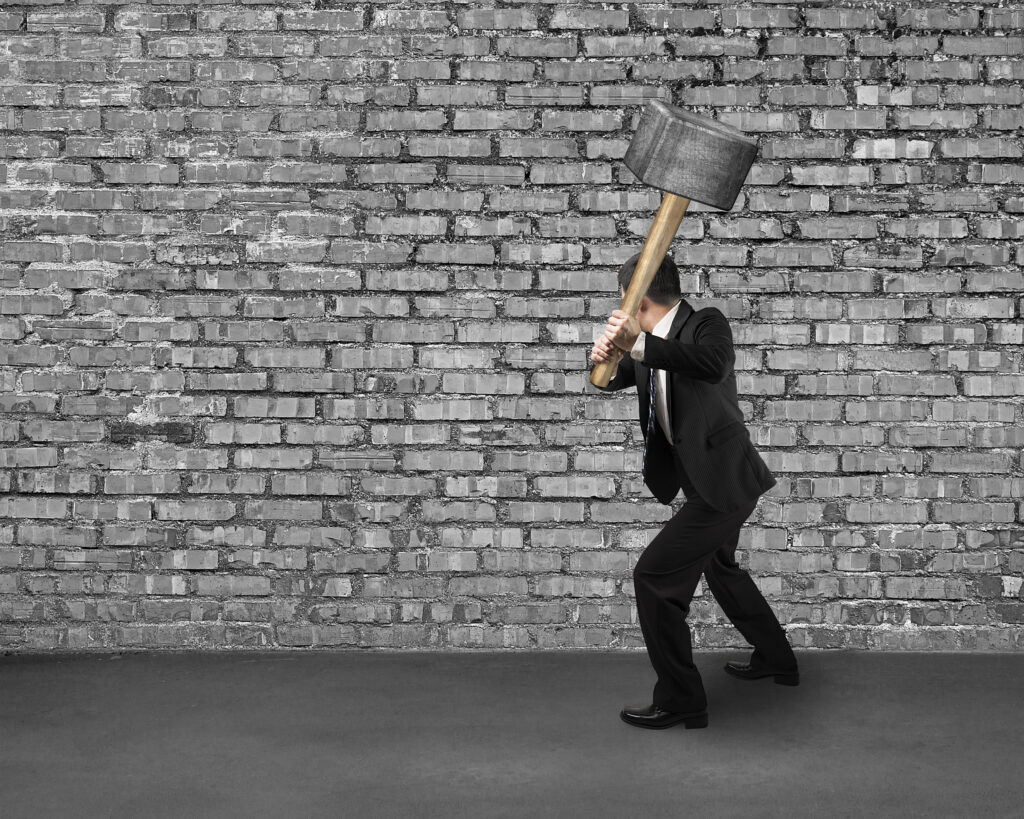man with hammer ready to hit a brick wall