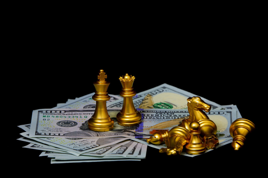 chess pieces sitting on a pile of $100 bills