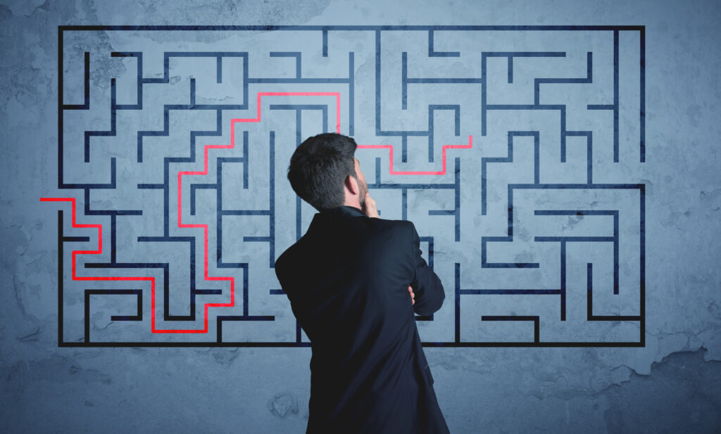 a man looking at a maze on a wall and tracing a red line through the maze in order to get out of the maze