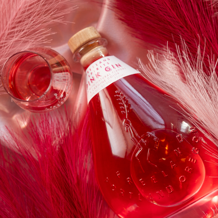 A BOTTLE OF FREELAND SPIRITS GIN WITH A GLASS HALF FULL